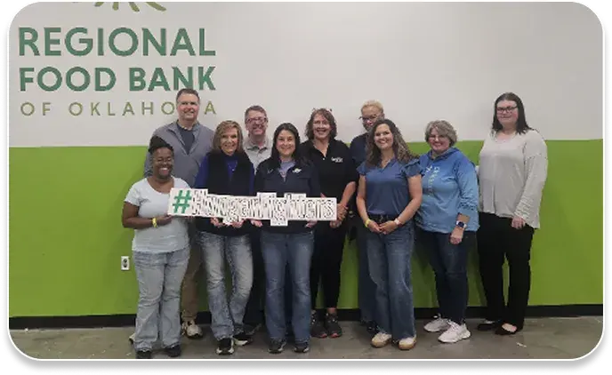 image shows volunteers standing in front of the wall at a local food bank