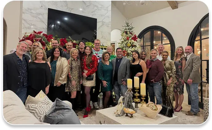 image shows coworkers standing in front of a decorated tree at a holiday party